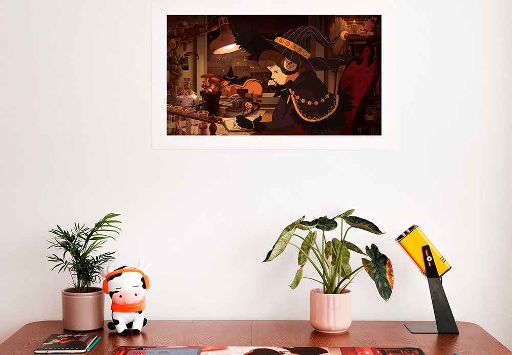 The same Halloween-themed print displayed on a wall above a desk. On the desk are a few plants, a mouse, a lamp, and a plush toy of a cow wearing headphones. The atmosphere is calm and creative, adding a cozy vibe to the work or study space.