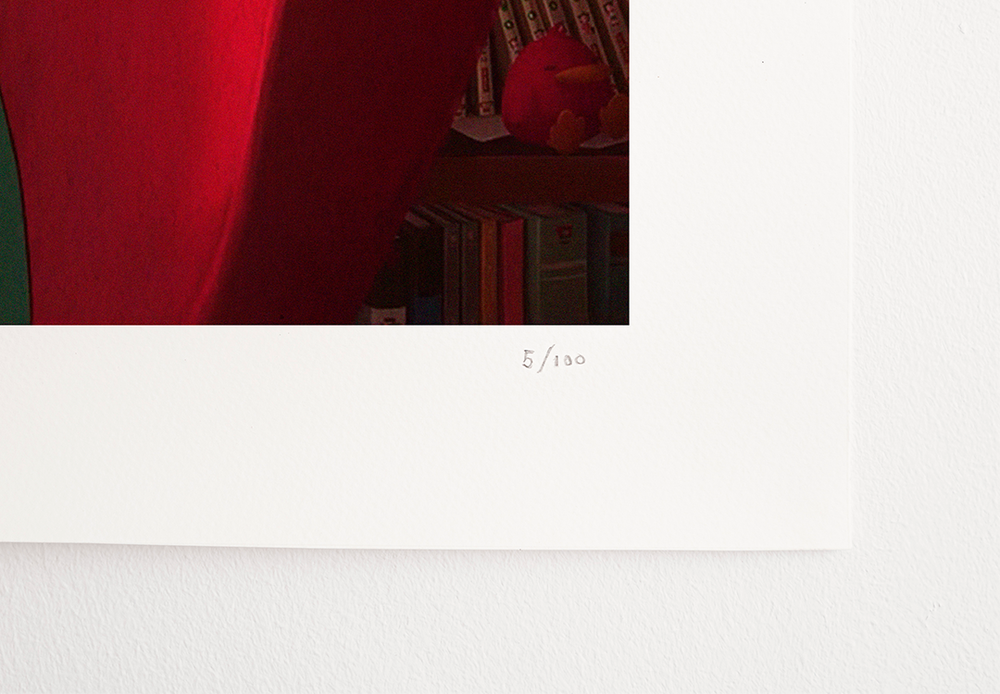 A close-up of the lower-right corner of a Lofi Girl print, showing the red back of a chair and bookshelves. The print is numbered '5/100' in pencil.