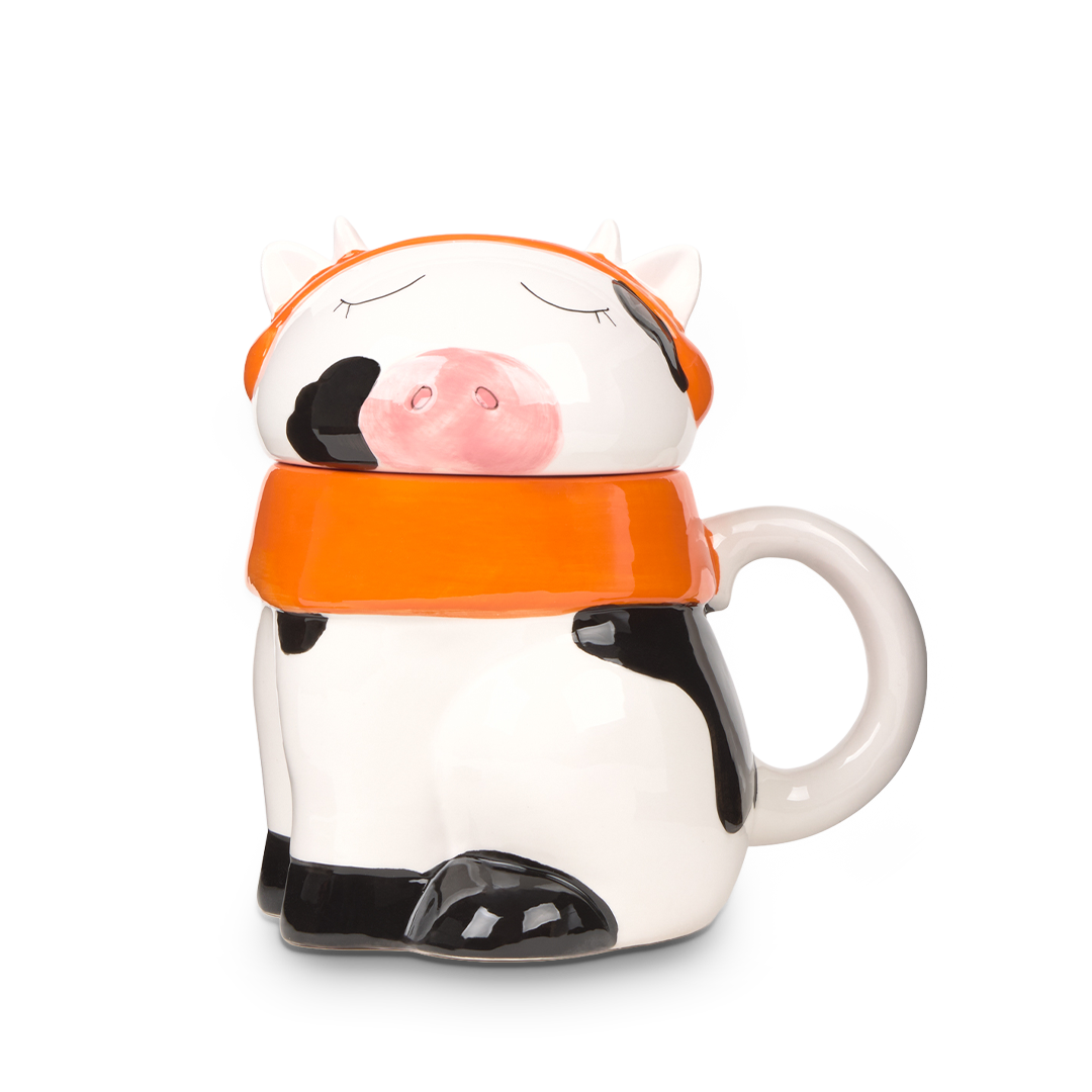 Ceramic mug shaped like a cow with an orange lid on a white background