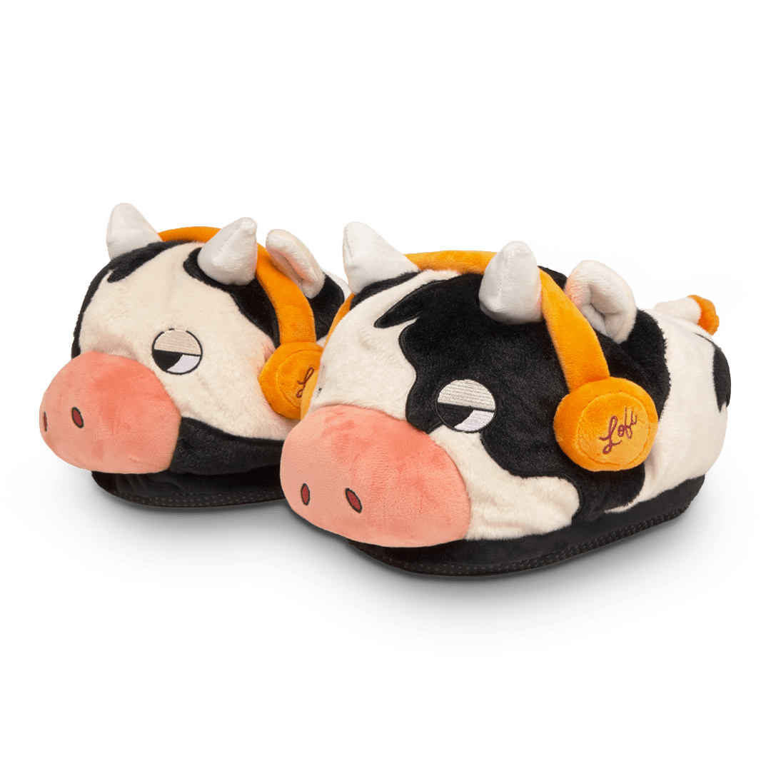 Pair of cow-themed slippers with orange bells on a white background