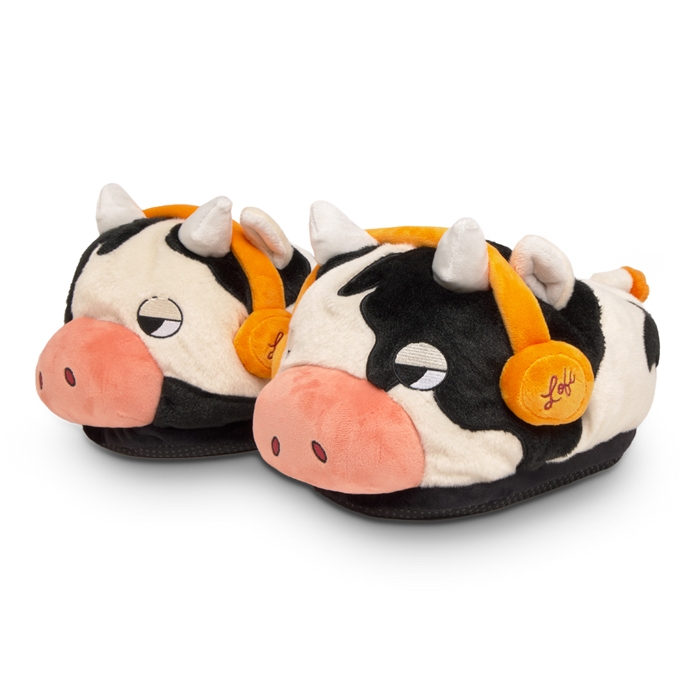 Pair of cow-themed slippers with orange bells on a white background