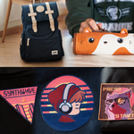 A navy blue backpack with beige straps sits next to an orange animal-shaped pencil case on a wooden surface. Below, there is a close-up view of three colorful embroidered patches featuring retro-style designs.