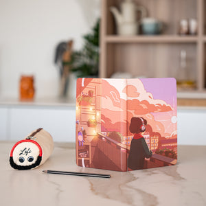 
                  
                    This image presents the headphone-themed pencil case alongside a notebook featuring a vibrant illustration of a serene rooftop scene at sunset. The notebook is opened, displaying a picturesque view that complements the cozy vibe of the pencil case. A pen lies beside the notebook, suggesting a peaceful moment of journaling or planning, while the blurred background enhances the focus on the study essentials.
                  
                