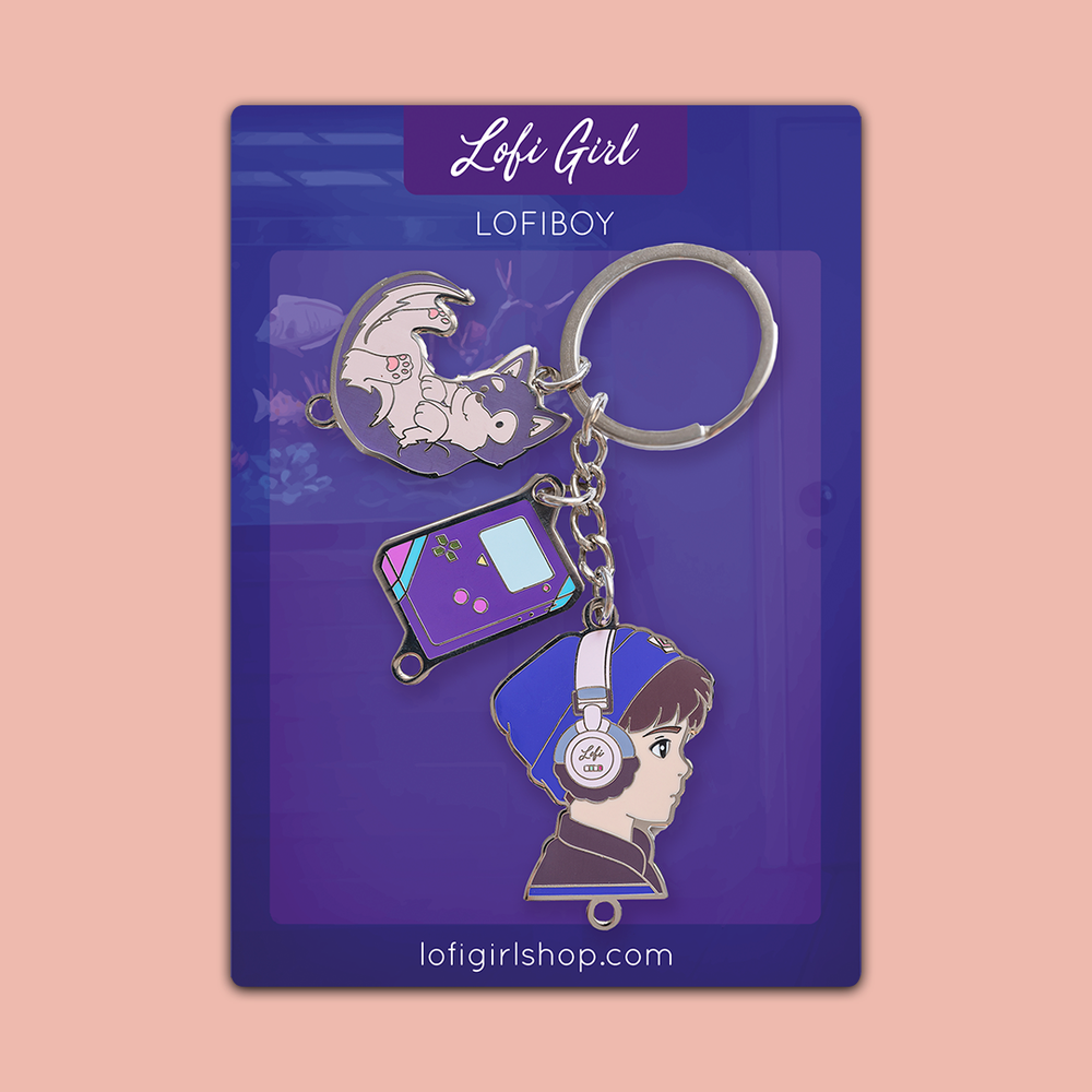 
                  
                    An illustrated keychain set featuring Lofi Boy, presented on a branded 'Lofi Girl' backing card with a purple background. The keychain includes three charms: a profile of Lofi Boy wearing a blue beanie and headphones, a retro-style handheld gaming device, and Lofi Boy Dog lounging on a crescent moon. The playful design captures the nostalgic and relaxing vibe associated with Lofi aesthetics.
                  
                