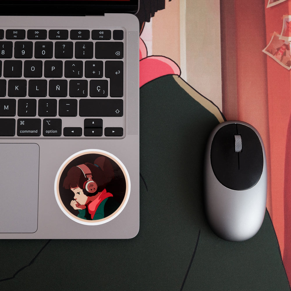 Close-up of a laptop on a "Lofi Girl" desk pad. A mouse is positioned on the right side of the laptop, and there is a circular sticker of the "Lofi Girl" character on the laptop's surface, showing her wearing headphones and resting her head on her hand.