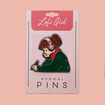 Enamel pin featuring Lofi Girl in a studying pose with headphones, on a branded card backing.