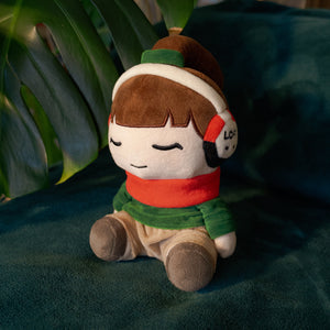 
                  
                    Plush toy with a character wearing a helmet, scarf, and headphones on a green fabric background.
                  
                
