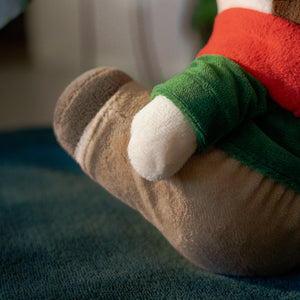 
                  
                    Close-up of a plush toy resembling a character with a red sleeve and green armrest.
                  
                