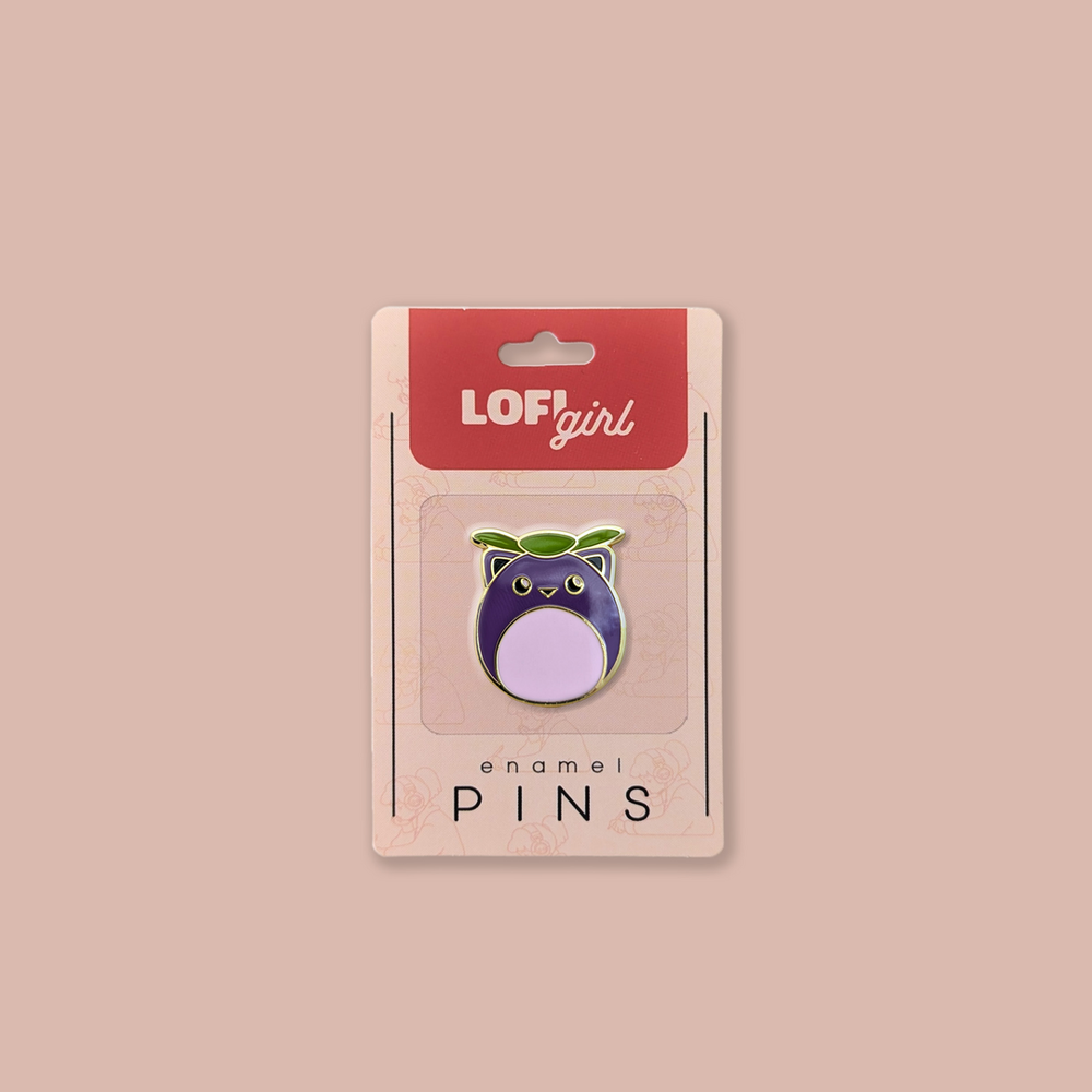 Lofi Girl enamel pin featuring a round, owl-like character with a purple body and a green leaf on its head. Packaged on a pink backing card with 'Lofi Girl' branding.