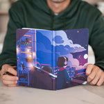 The Nighttime Bullet Journal is open, revealing a vibrant, nighttime cityscape on its cover. A person holds the journal, displaying the intricate design featuring Lofi Girl gazing at the starry sky from a rooftop garden. The deep blue and purple hues create a calming ambiance, perfect for late-night reflections.