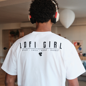 
                  
                    Back view of a person wearing a white Lofi Girl t-shirt with the bold black text 'Lofi Girl' across the back, accompanied by the tagline 'Study • Chill • Sleep • Repeat' and a small fist icon. They are wearing headphones and standing in a modern, tastefully decorated room, conveying a laid-back and focused vibe.
                  
                